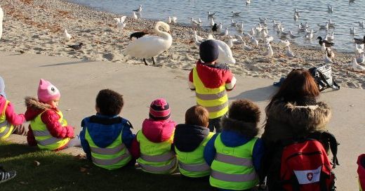 enfants assis au bord du lac avec leur éducatrice